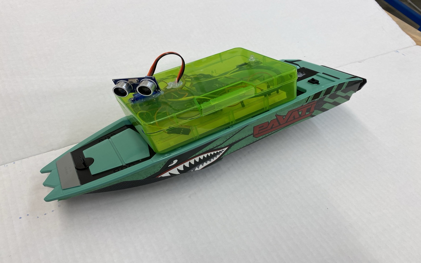 RC boat showing ultrasonic sensor on servo mount and transparent electronics enclosure