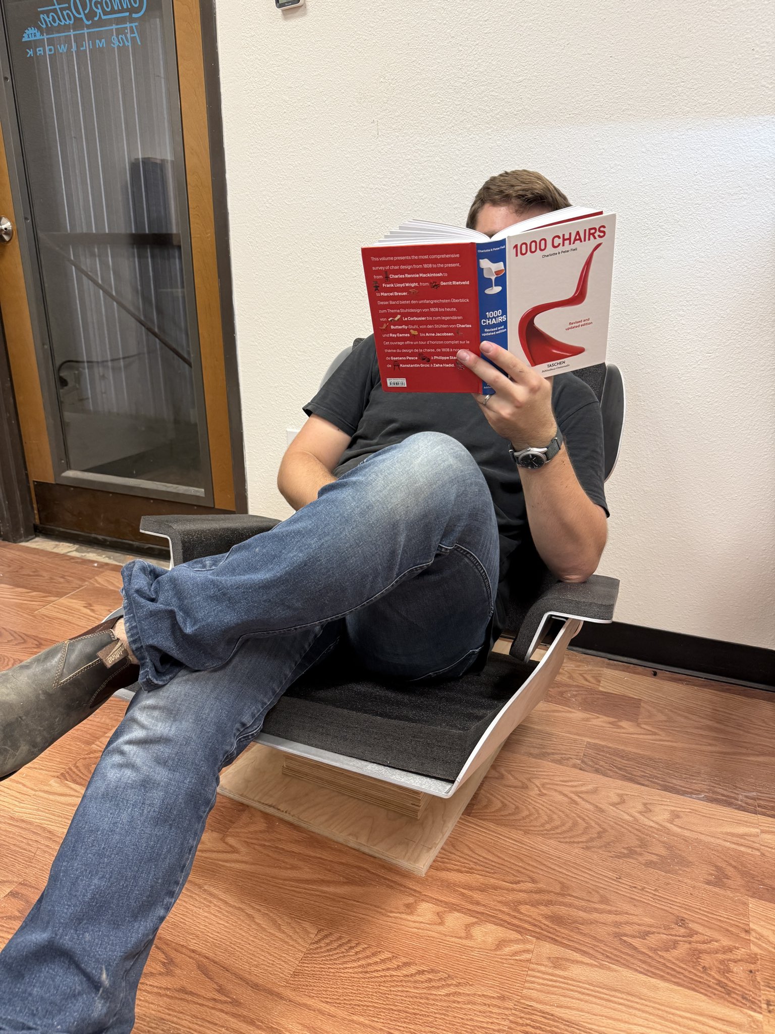Zach sitting in the Seames Lounge Chair reading the book 1000 Chairs