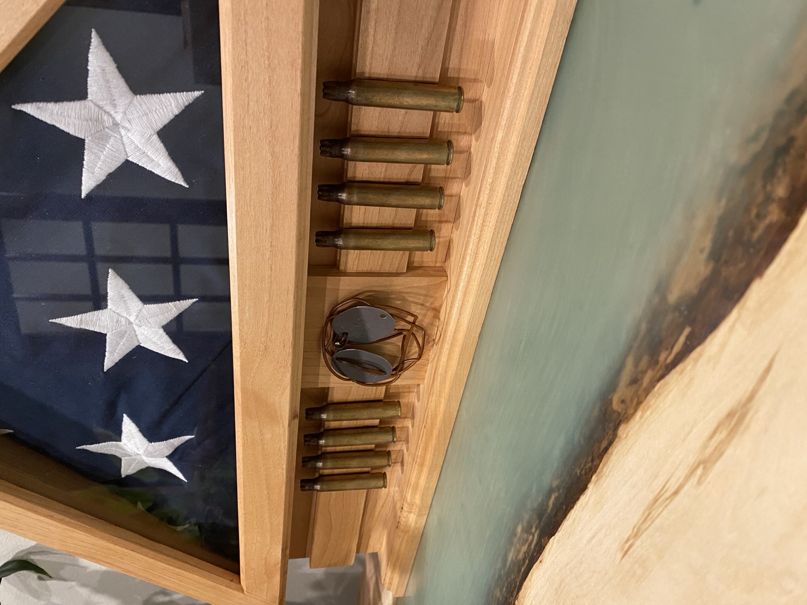 Close-up of bullet casings and dog tags between flag glass and live-edge panel