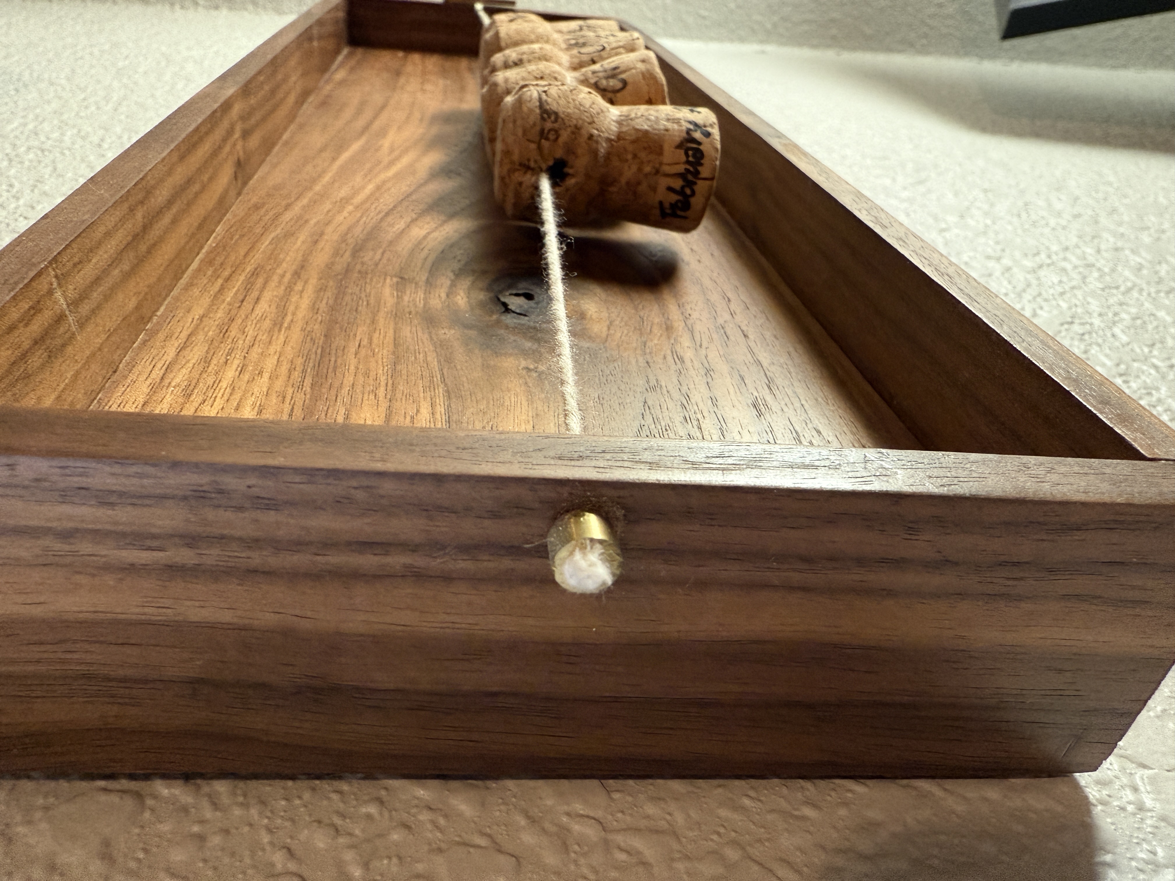 Close-up of the walnut tray showing brass pin detail and corks with handwritten dates