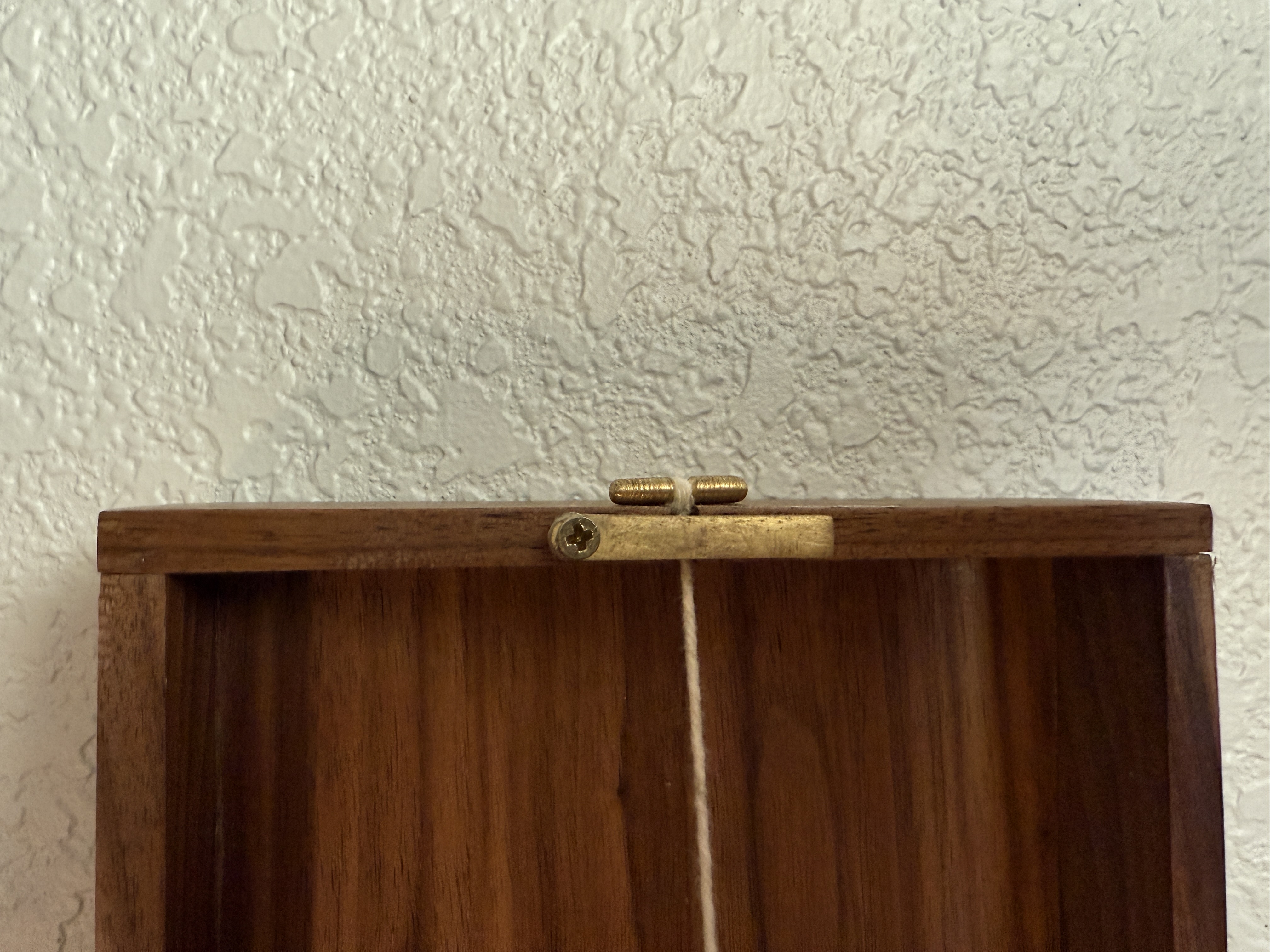 Detail of the custom brass cleat used to tension the string at the top of the display