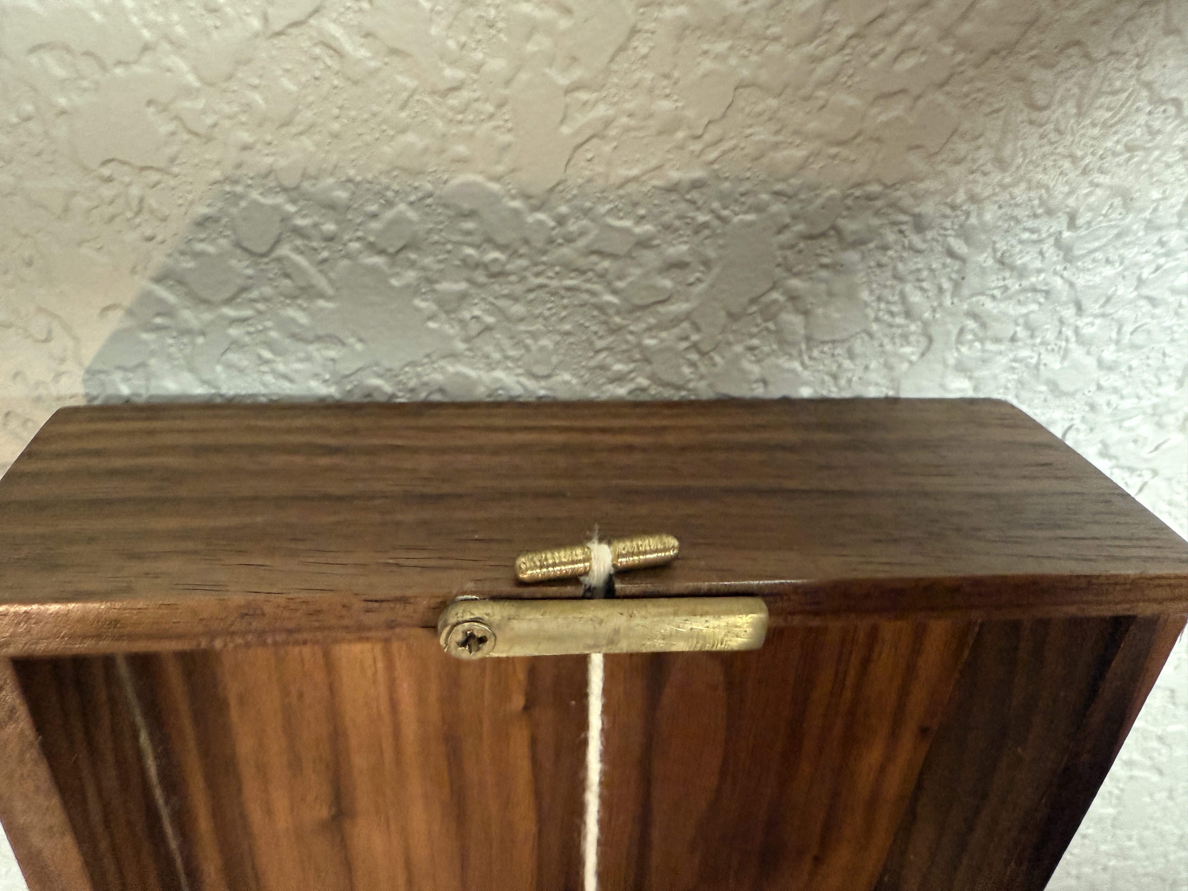 Close-up of the brass cleat with string wrapped around it against the walnut frame