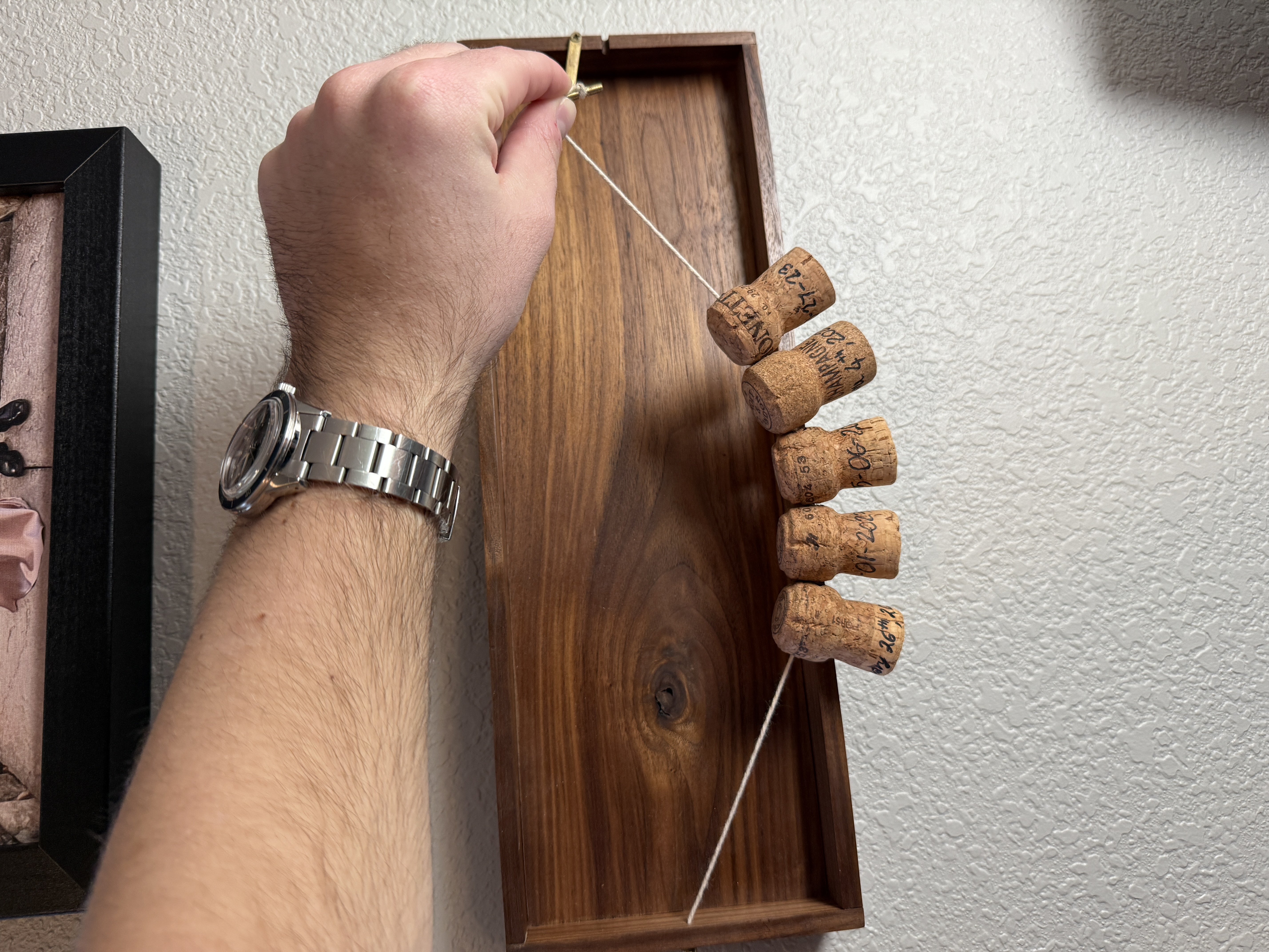 Memory holder mounted on the wall with corks hanging from the string