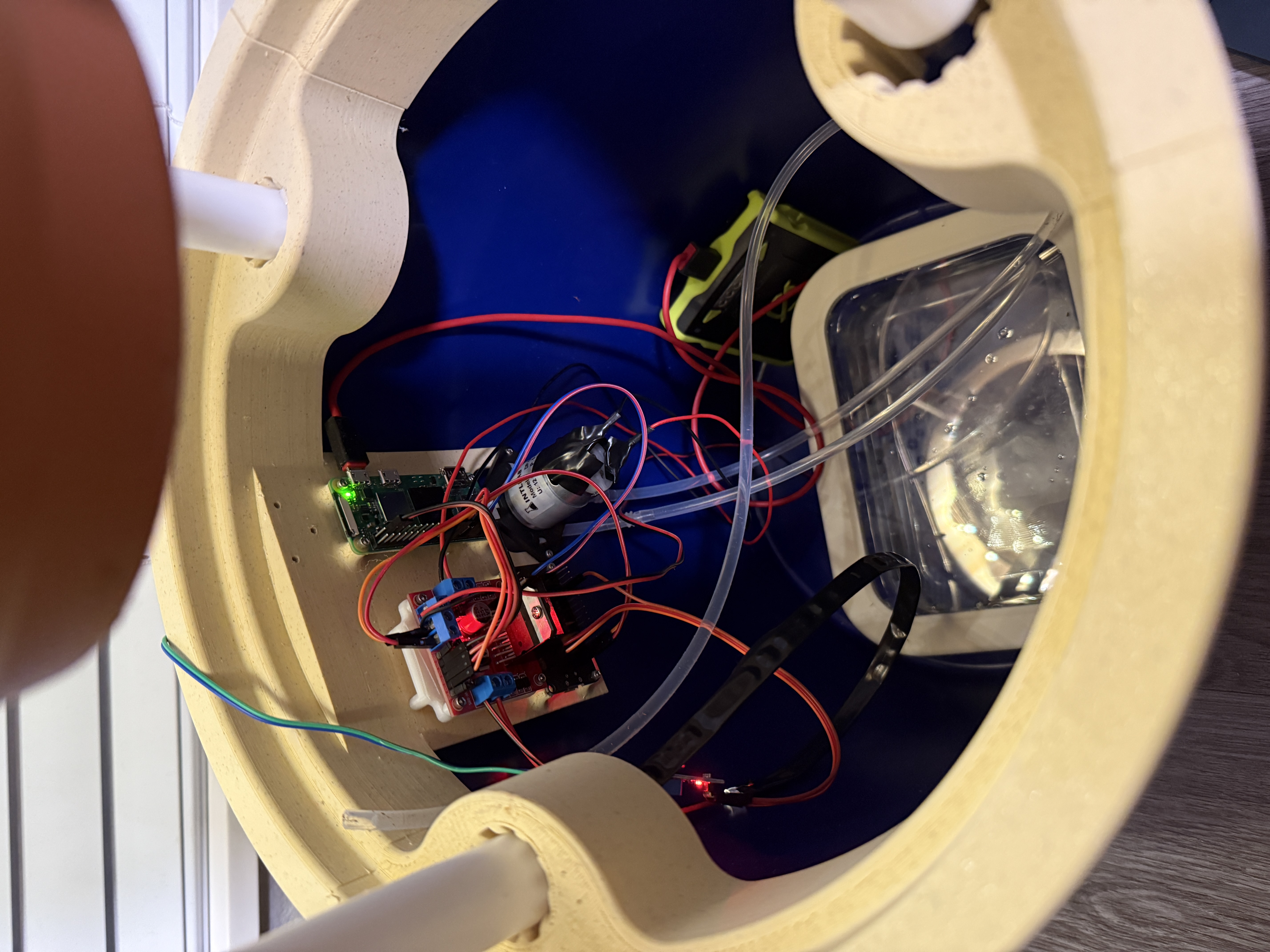 Interior electronics bay beneath the planter showing peristaltic pump, soil moisture sensor wiring, and microcontroller
