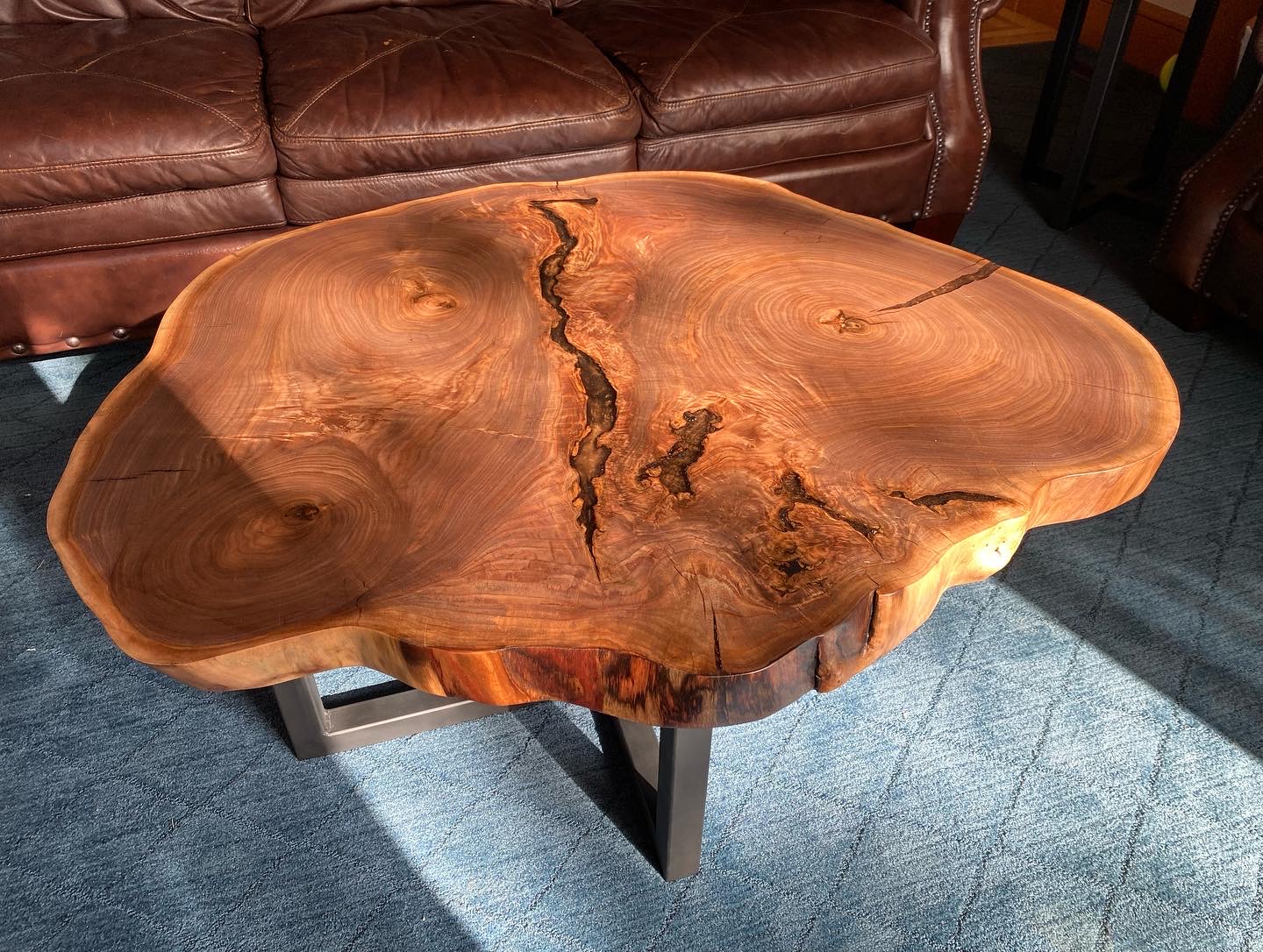 Finished walnut cookie slab coffee table with epoxy-filled voids on welded steel base